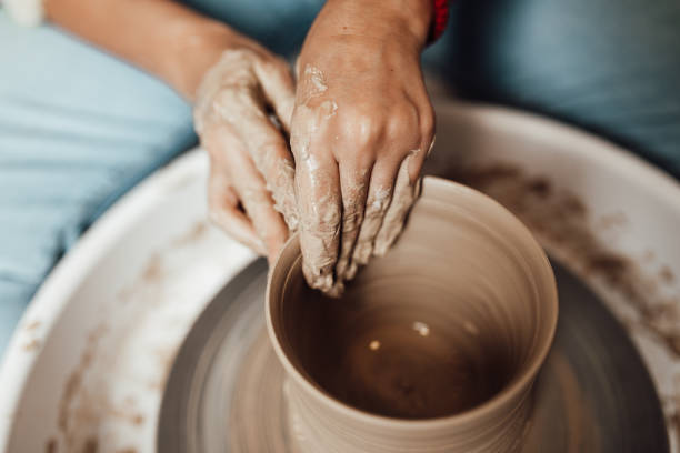 mãos mexendo com massa de cerâmica moldando um vaso